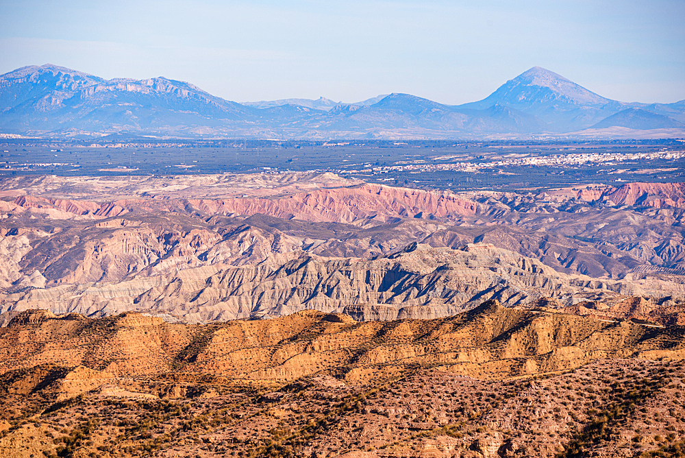Panoramic landscape of the Gorafe badlands, with dramatic cliffs and barren valleys under a clear Andalusian sky.