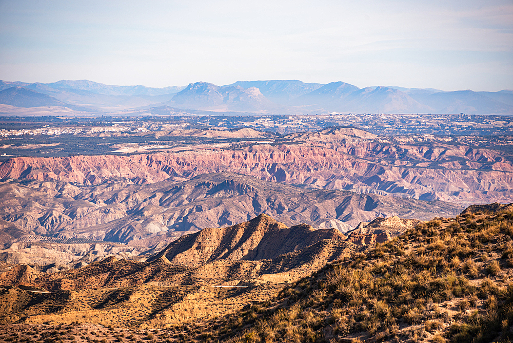 Expansive view over the eroded canyons and rugged terrain of the Desierto de Gorafe in Granada, Spain, with layered badlands stretching to the horizon.