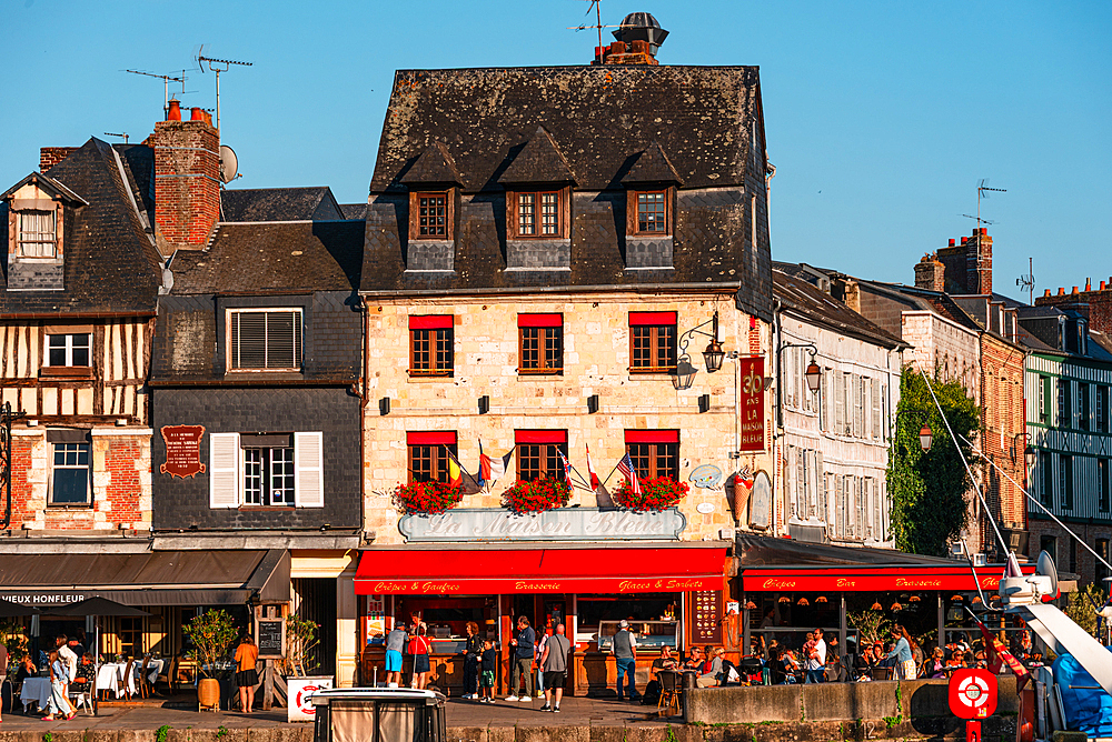 Charming half-timbered houses with colorful shutters and flowers in Honfleur, Normandy’s historic old town.