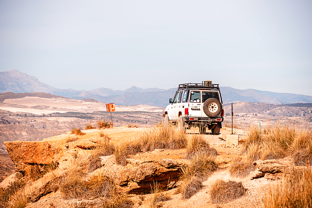 4x4 parked on the edge of a cliff in the Desierto de Gorafe, Granada, Spain