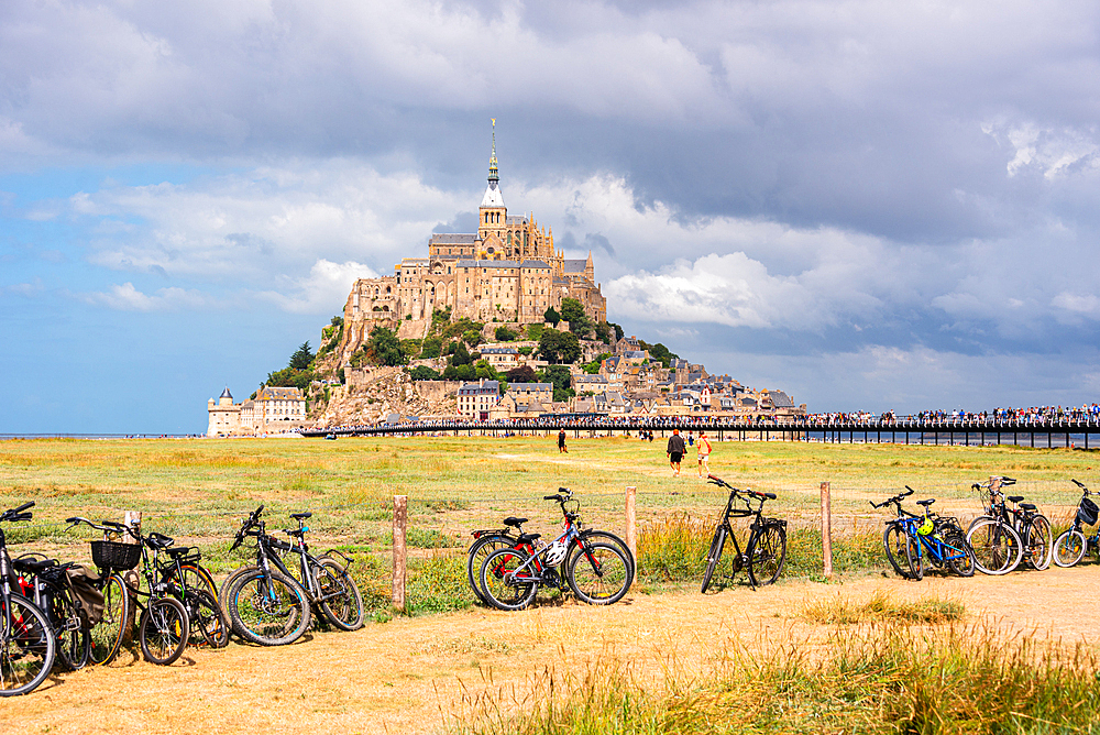 Row of bicycles parked with Mont Saint-Michel visible across the fields in the distance, Normandy, France
