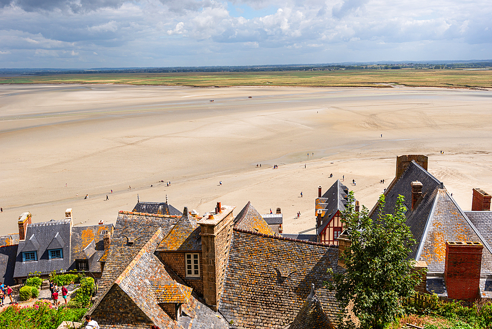 View over rooftops of Mont Saint-Michel village with the vast tidal bay stretching out to the horizon, Normandy, France