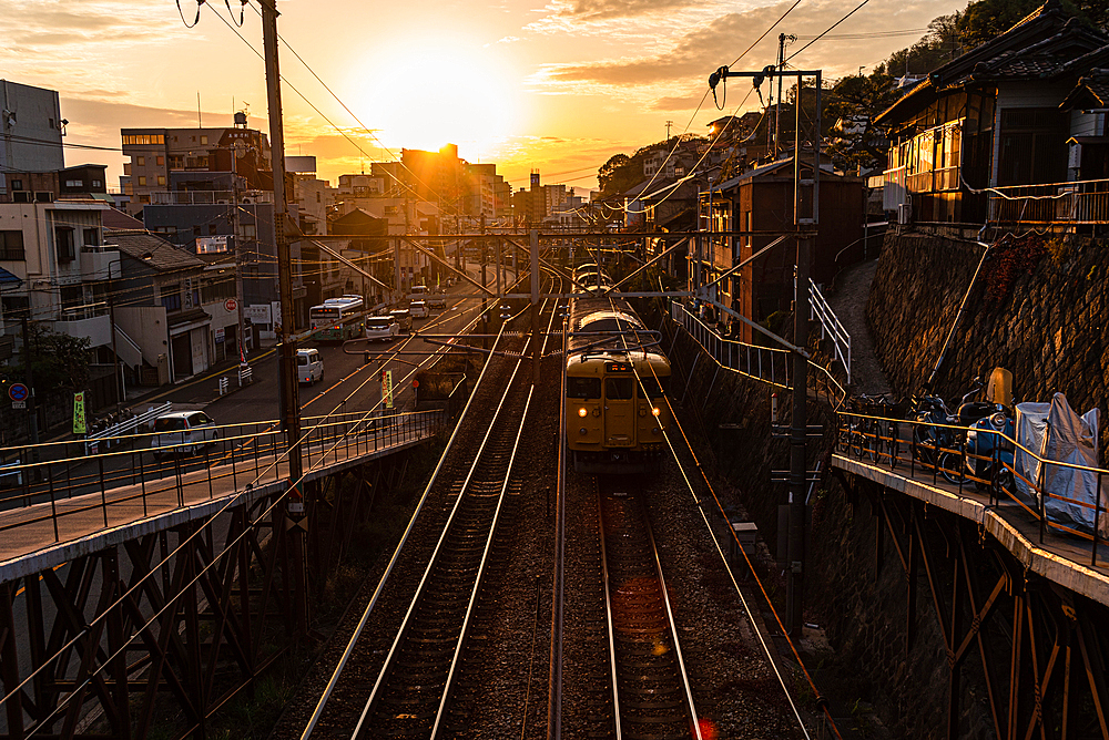 View from a railway bridge with a yellow Japanese train approaching during sunset, Onomichi, Honshu, Japan, Asia