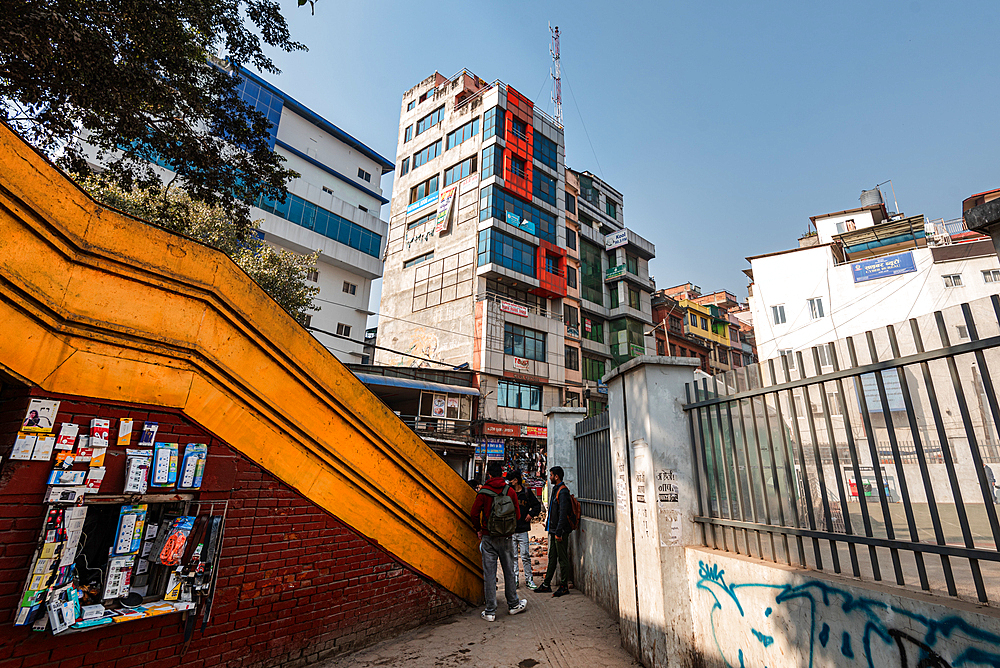 Yellow pedestrian bridge and fences leading the eye to an intricate building on New Road, Kathmandu, Nepal, Asia