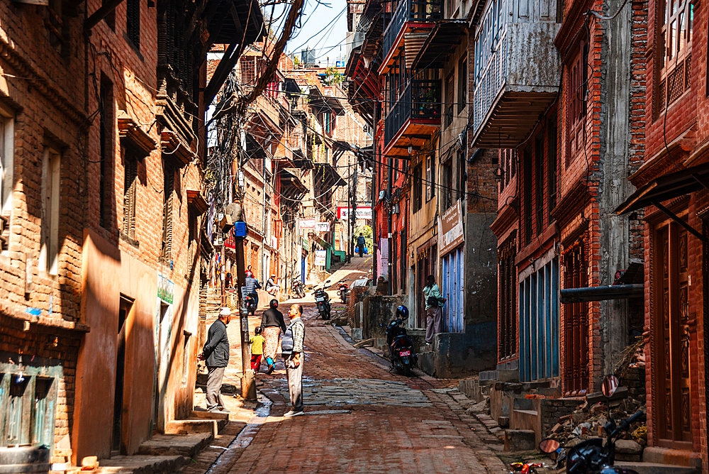 View along a narrow alley road with traditional brick houses in the center of Bhaktapur, Kathmandu, Nepal, Asia