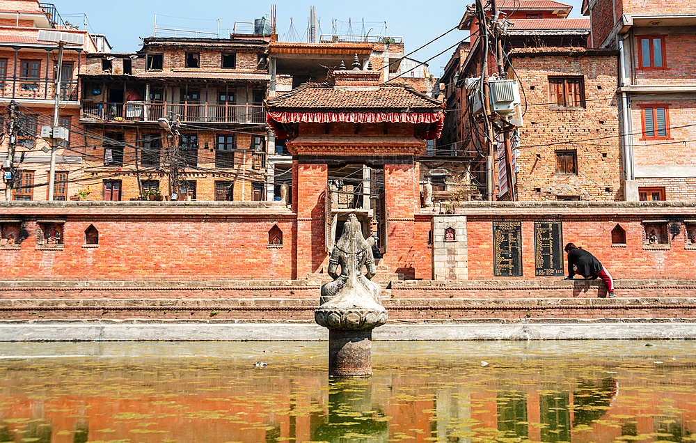 Statue of Shiva in the green waters, Tekha Pukhu (Tekha Pokhari) water basin with traditional brick work architecture of Bhaktapur, Nepal, Asia