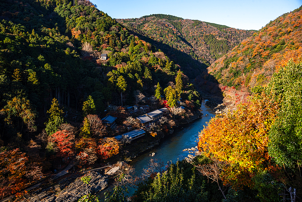 Autumnal forests with deep blue Katsura Riverwith temple roofs on the river bank in Arashiyama of Kyoto, Honshu, Japan, Asia