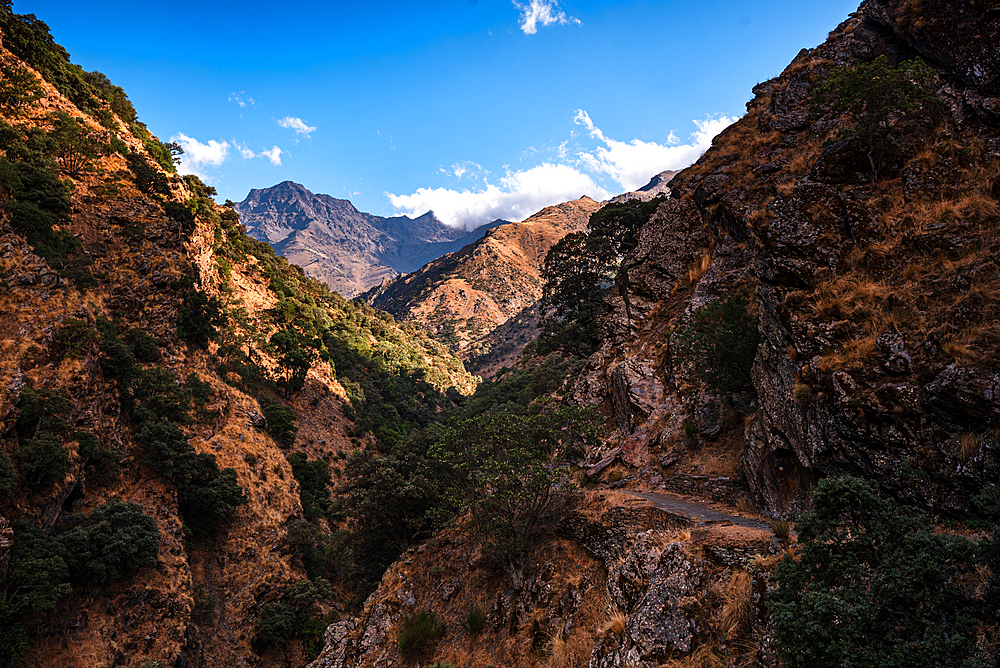 Hiking trail along rugged arid mountain valley of the Sierra Nevada, with Alcazaba in the distance, Andalusia, Spain, Europe