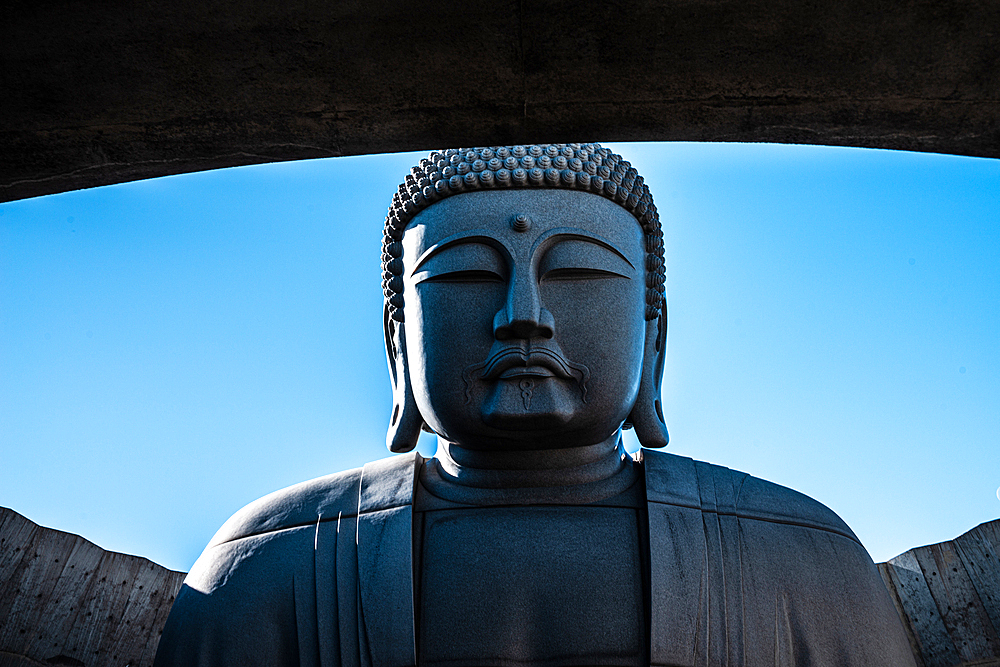 Close up of the upper body and head of a giant Buddha statue agains a blue sky, Hill of the Buddha, Sapporo, Hokkaido, Japan, Asia