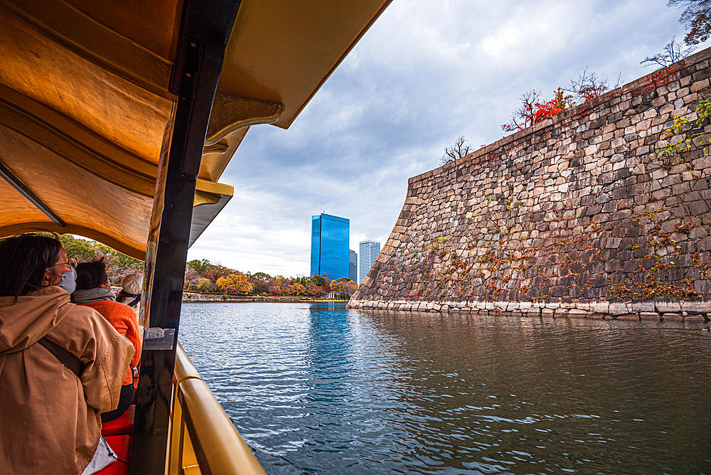 View from a traditional boat on the Osaka Castle Moat and walls in autumn with visitors sightseeing, Osaka, Honshu, Japan, Asia