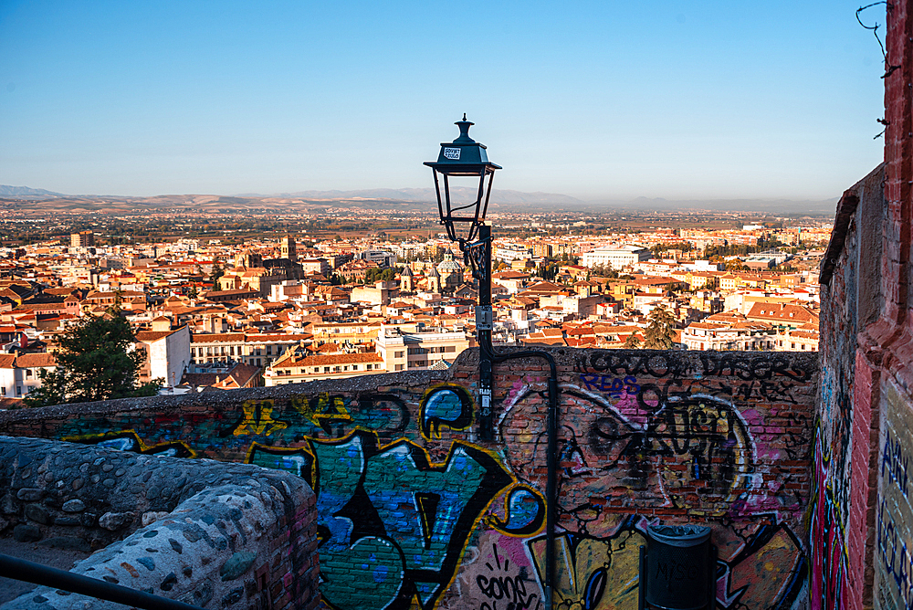 Walls and lantern in front of the skyline of Granada at sunrise. Albaicin, Granada, Andalucia, Spain