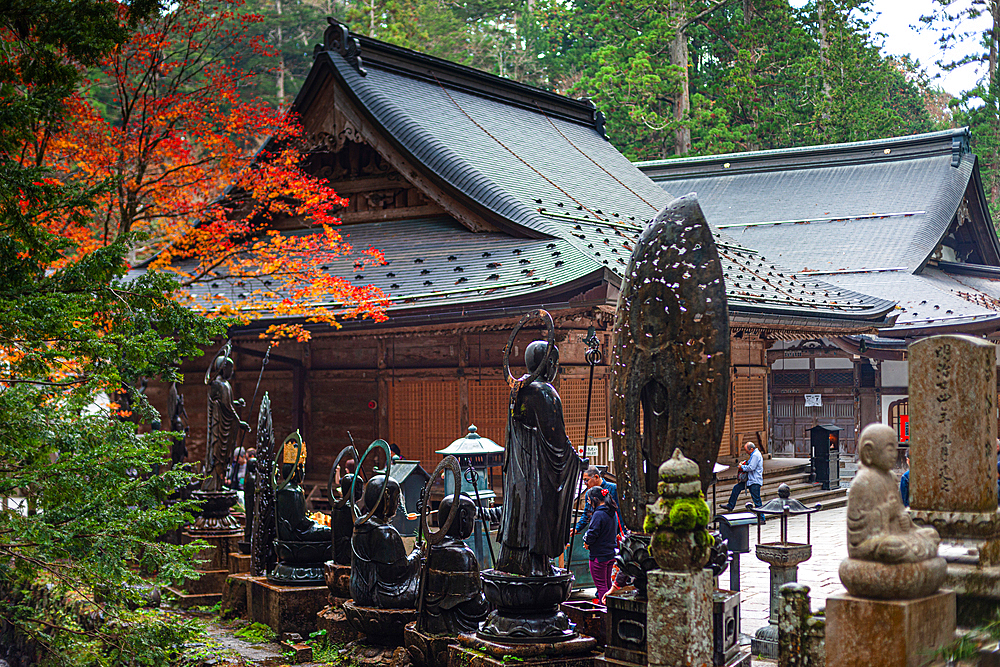 A traditional Japanese temple surrounded by gravestones and vibrant autumn foliage in the sacred grounds of Koyasan, Japan.Kongobu-ji Okuno-in