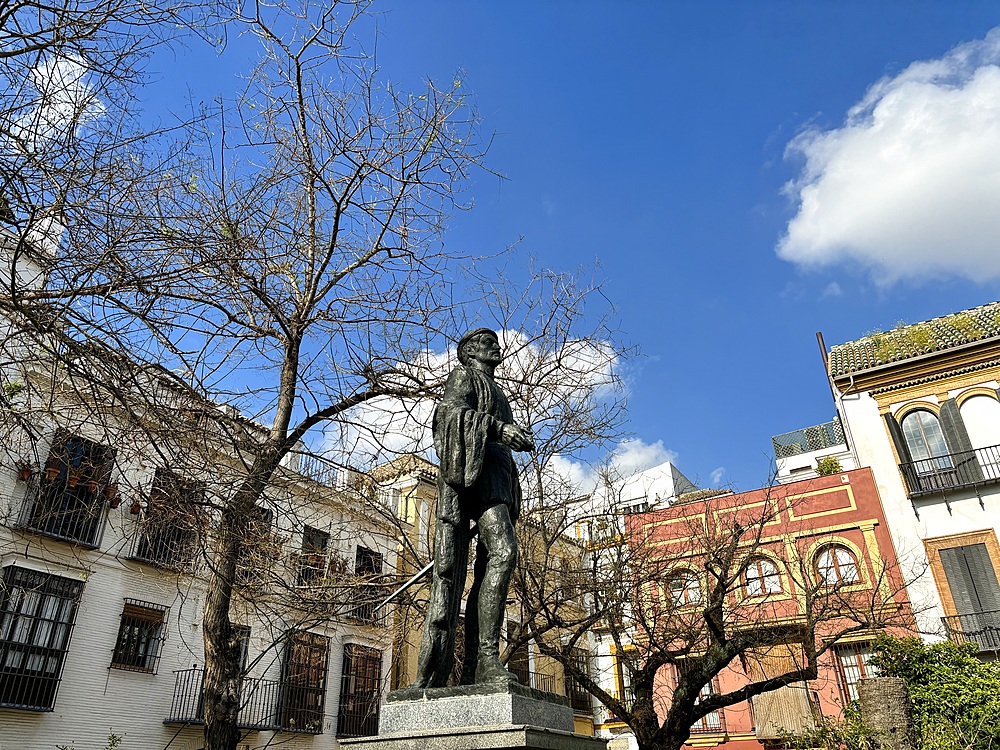 View of the Plaza de los Refinadores monument in Seville, featuring a life-size bronze sculpture of Don Juan Tenorio, a fictional character from Spanish literature. The sculpture depicts Don Juan adorned in typical 17th-century attire.