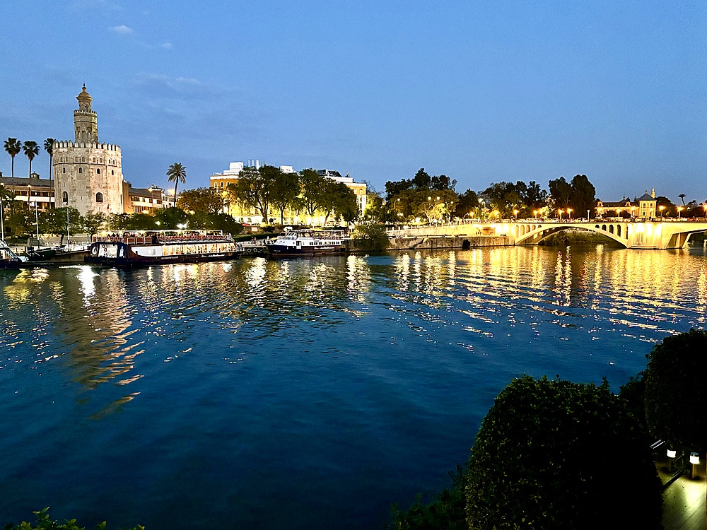 Sunset view of the Guadalquivir River in Seville, Spain with the Torre del Oro (Tower of Gold), a dodecagonal military watchtower erected by the Almohad Caliphate in order to control access to Seville via the river on the left.