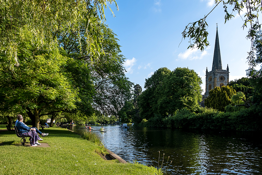 Scenic view of the River Avon in Stratford-upon-Avon, England, on a sunny day with Holy Trinity Church in the background. Known as Shakespeare's Avon, this historic river flows through the market town, famous as the birthplace of William Shakespeare.