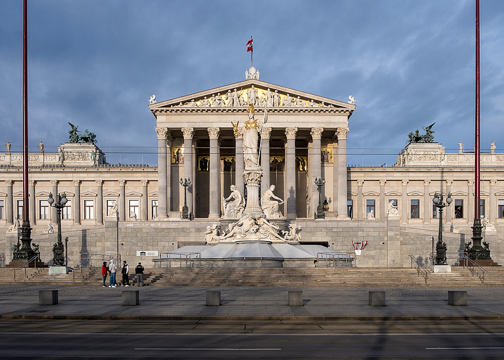 Vienna, Austria – View of the Austrian Parliament's grand neo-Greek entrance facade on Ringstrasse, featuring the monumental Pallas Athena fountain and sculpted ramp of the Theophil Hansen-designed building.