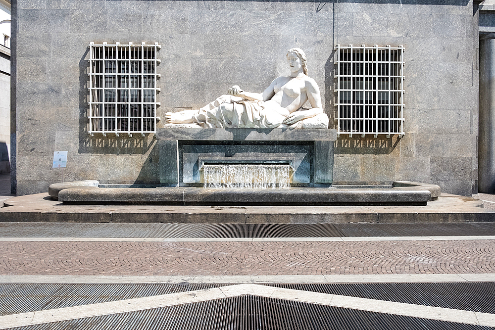 View of the Fountain of Dora in Via Roma, executed by Umberto Baglion, 1893-1965, and placed in 1939, the allegorical statue represents the River Dora with a woman lying on a pedestal, from which water flows, Turin, Piedmont, Italy, Europe