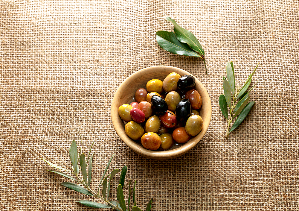 Olives in olive oil in a small bowl, with leaves, on a canvas, Istanbul, Turkey, Europe