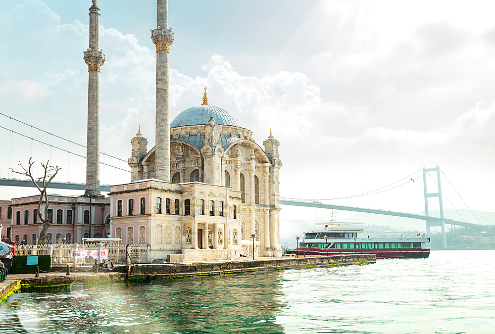 Glowing Ortakoy Mosque in the rays of the sun in cloudy weather, Istanbul, Turkey, Europe