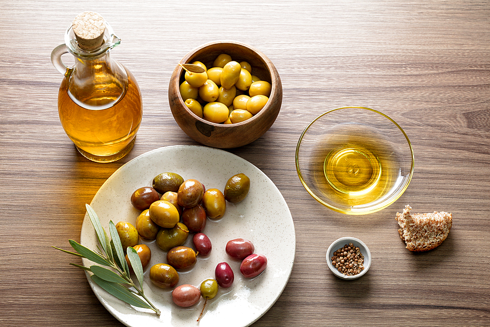 Olives with bunch of leaves in a white plate and olive oil on wooden background, Flatlay concept, Turkish organic olives, Bursa, Turkey, Asia Minor, Eurasia