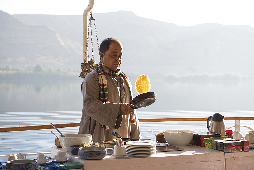 Cook preparing breakfast pancakes on the upper deck of the dahabeah, passenger river boat of the Lazuli fleet, sailing on the Nile river, Egypt, North Africa, Africa