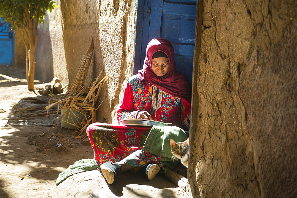 Woman sitting on her doorstep peeling garlic, village of Ramadi, west bank of the Nile south of Edfu, Egypt, North Africa, Africa