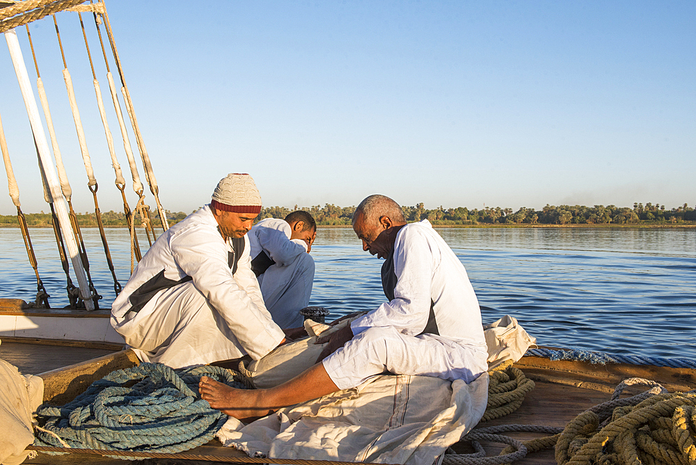 Members of the crew sitting at the prow of a dahabeah, passenger river boat of the Lazuli fleet, sailing on the Nile river, Egypt, North Africa, Africa