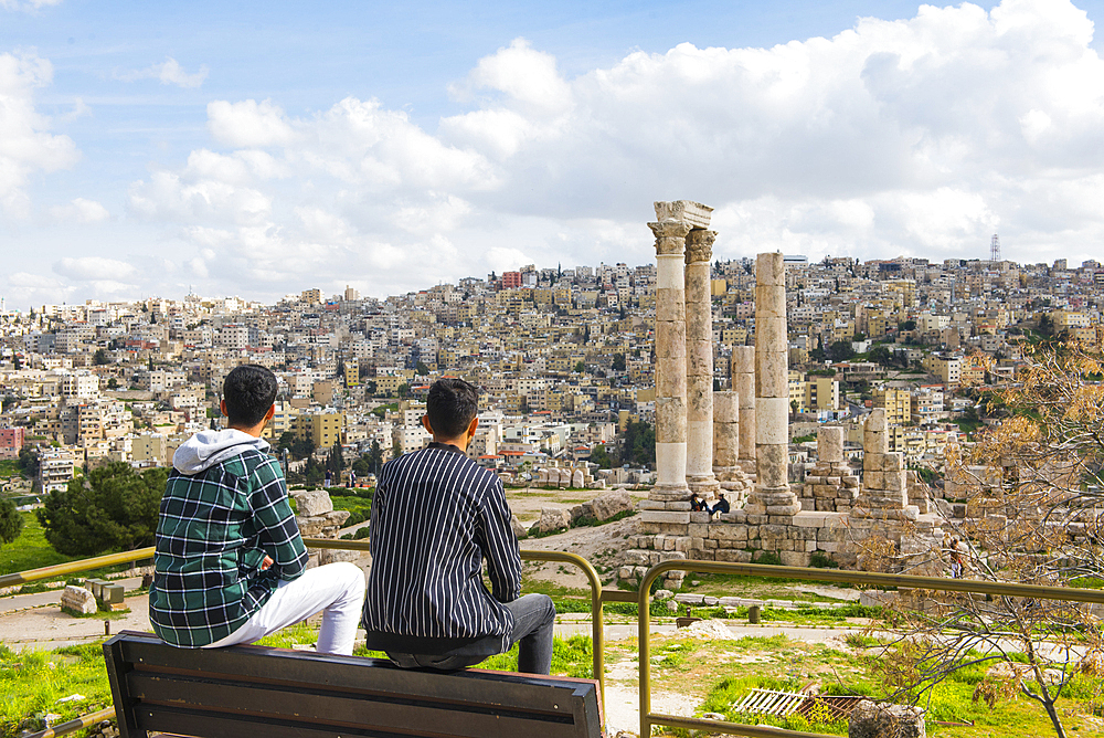 Two young Jordanian men sitting on a bench facing the Temple of Hercules within the Amman Citadel (Jabal al-Qal'a), historic site located on top of a hill in the heart of Amman, Jordan, Middle East