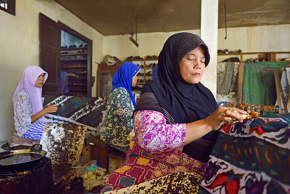 women using a pen-like tool, called 'canting', to apply liquid hot wax in the batik-making process, Wirakuto batik workshop, Pekalongan, Java island, Indonesia, Southeast Asia