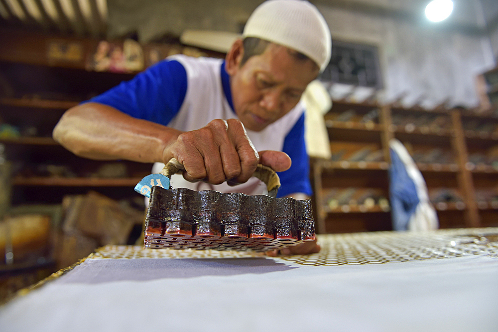 Workers applying wax-resist using a copper plate stamp (cap), Wirakuto batik workshop, Pekalongan, Java island, Indonesia, Southeast Asia, Asia