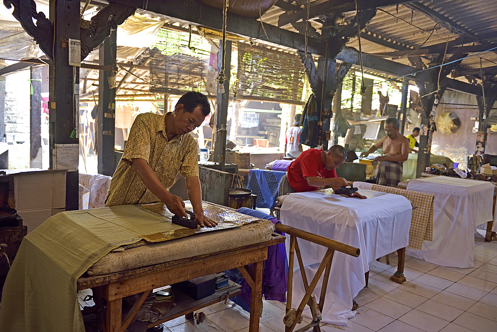 workers applying wax-resist using a copper plate stamp (cap), Wirakuto batik workshop, Pekalongan, Java island, Indonesia, Southeast Asia