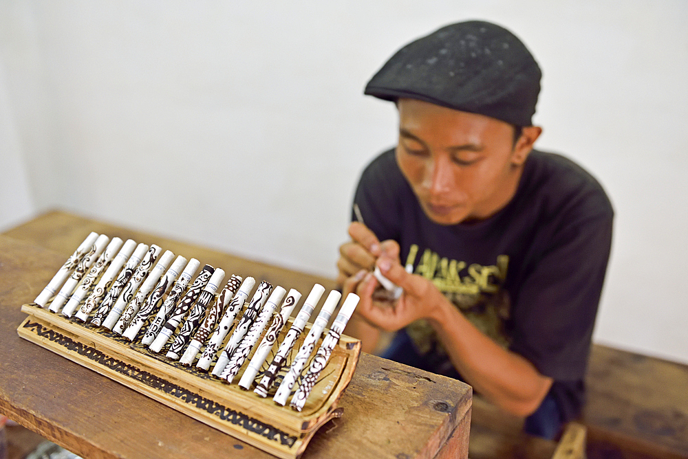 Man painting batik pattern with coffee grounds on cigarettes, Tapel Koeda Kretek (Clove Cigarette) Factory at Juwana, Java island, Indonesia, Southeast Asia, Asia