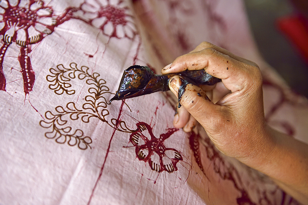 woman using a pen-like tool, called 'canting', to apply liquid hot wax to create pattern on the fabric before dyeing, workshop of Kidang Mas Batik House, Lasem, Java island, Indonesia, Southeast Asia