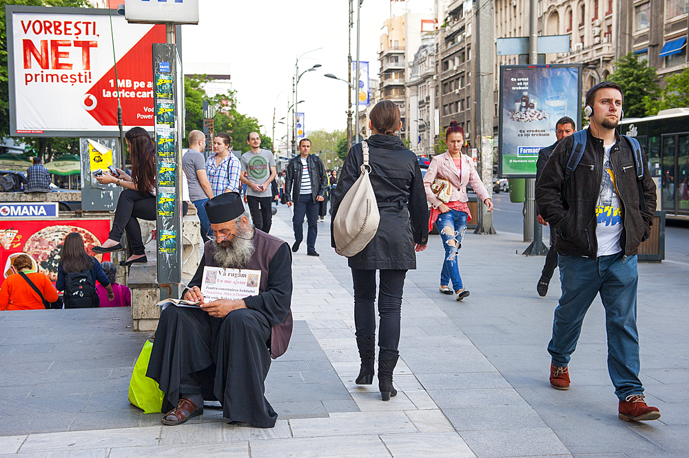 Orthodox priest taking the collection at Piata Romana underground station, General Gheorghe Magheru boulevard,Bucharest,Romania,Southeastern and Central Europe