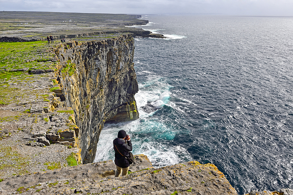 people taking pictures of the cliffs from Dun Aengus, prehistoric hill fort, Inishmore, the largest of the Aran Islands, Galway Bay, West Coast, Republic of Ireland, North-western Europe