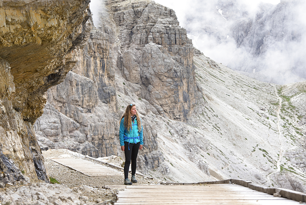 hiker on the path connecting the refuges Locatelli (Dreizinnenhutte) and Pian di Cengia (Bullelejochhutte) with the Punta dei Tre Scarperi (Dreischusterspitze) in the background, Three Peaks nature park, Trentino-Alto Adige, Sudtyrol, South Tyrol, Italy,