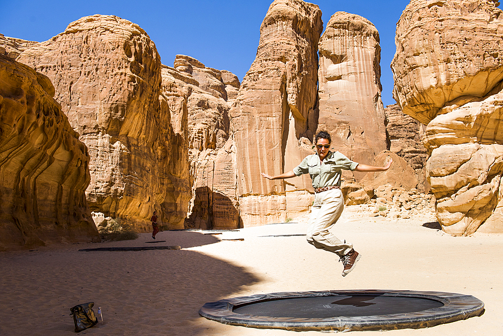 Woman jumping on a trampoline (puddle), installation by artist Manal Aldowayan, entitled 'Now you see Me, Now You Don’t' as part of the 2020 Desert X AlUla exhibition, which took place in the Ashar Valley, Medina Province, Saudi Arabia, Middle East, Medin