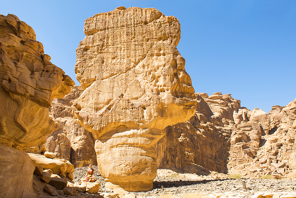 Woman practicing yoga poses among sandstone rock formation in the desert canyons of the Ashar Valley, Medina Province, Saudi Arabia, Middle East