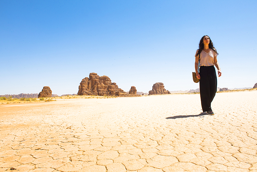 Woman walking on a large dry salt lake in the Sharaan Nature Reserve, AlUla, Medina Province, Saudi Arabia, Middle East