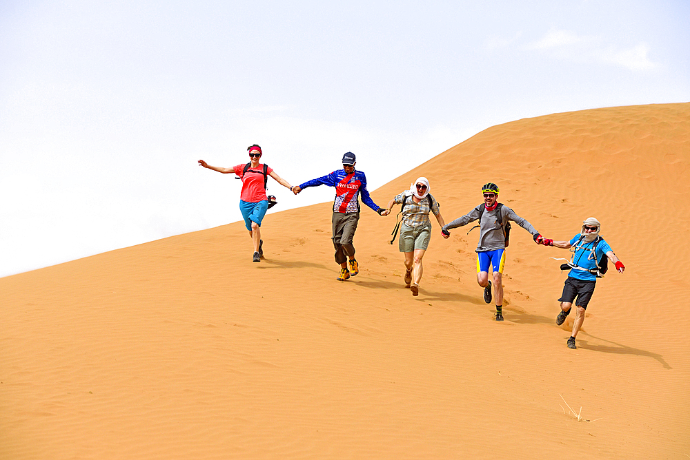 Group of people rushing down one of the sand dunes at Tinfou, near Tamegroute, Draa River valley, Province of Zagora, Region Draa-Tafilalet, Morocco, North West Africa