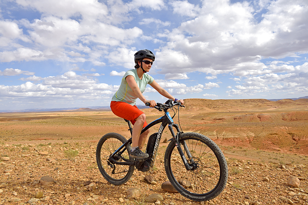 Rider on mountain bike with electric assistance on a track between Ouarzazate and Ait Ben Haddou, Ounila River valley, Ouarzazate Province, region of Draa-Tafilalet, Morocco, North West Africa