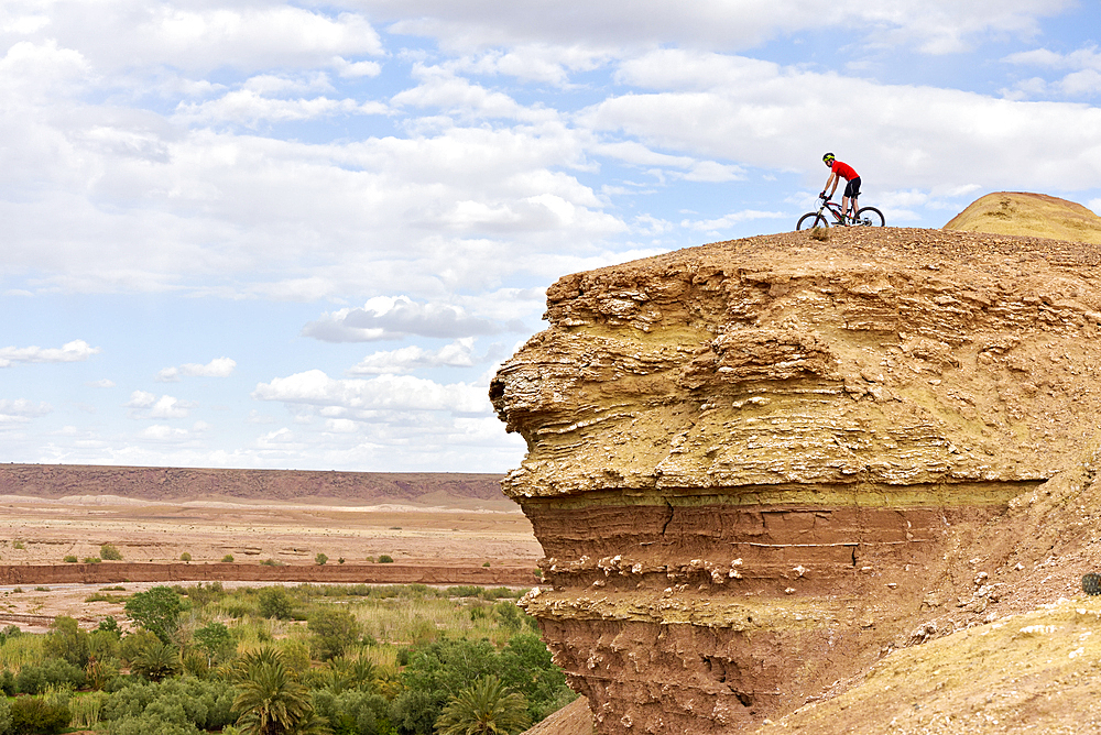 Cyclist on a promontory facing the Ksar of Ait-Ben-Haddou, Ounila River valley, Ouarzazate Province, region of Draa-Tafilalet, Morocco, North West Africa