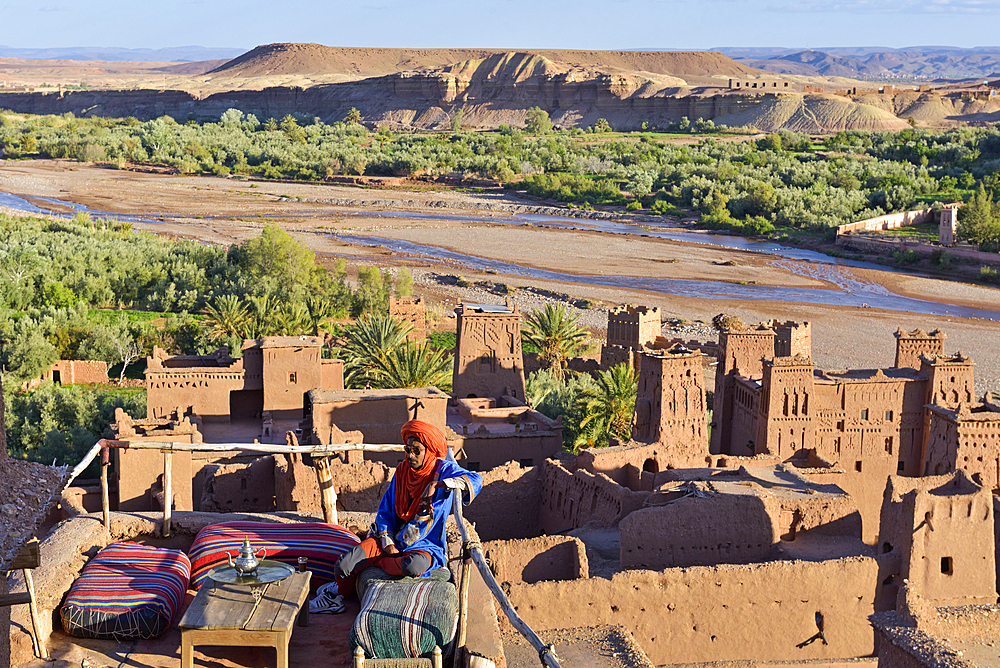 Man sitting on the terrace of a cafe overlooking the Ksar of Ait-Ben-Haddou, Ounila River valley, Ouarzazate Province, region of Draa-Tafilalet, Morocco, North West Africa