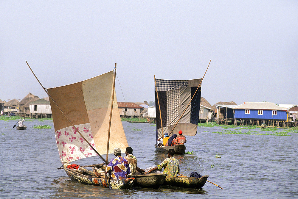 Villagers moving by sailing pirogue on Ganvie lake village in Lake Nokoué, near Cotonou, Gulf of Guinea, West Africa