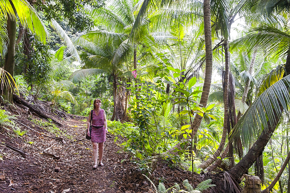 Woman walking on a path in the forest on the small Rolas (turtledove) island in the south of Sao Tome Island, Republic of Sao Tome and Principe,Africa