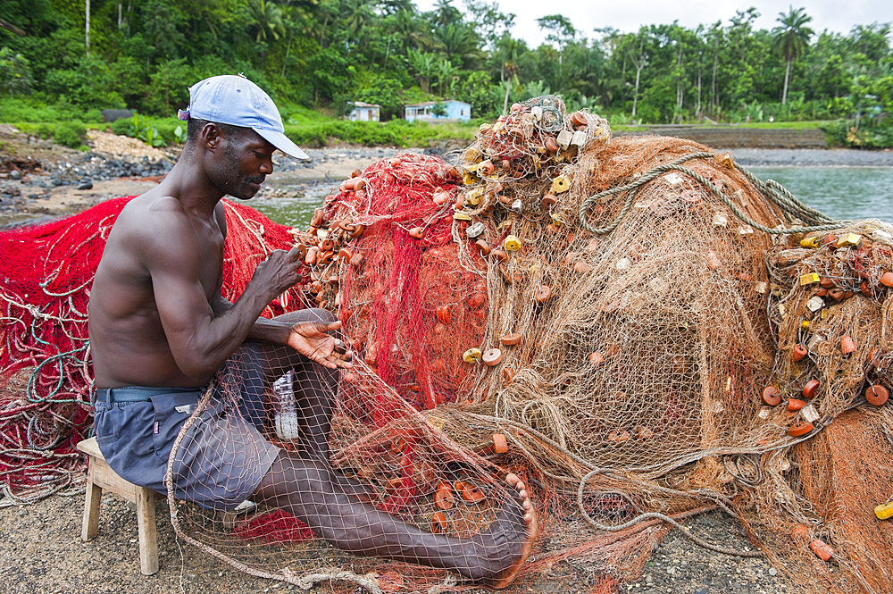 Man mending fishing net at Porto Alegre village in the south of Sao Tome Island, Republic of Sao Tome and Principe,Africa
