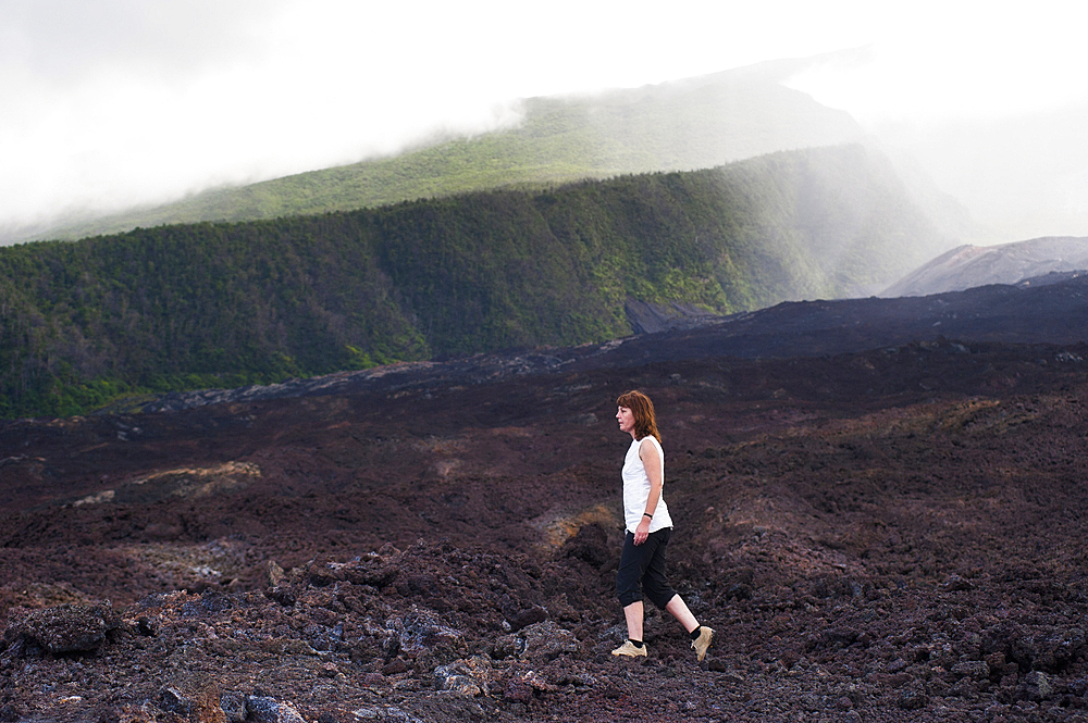 Woman walking on cold lava flow on the coast named 'Le Grand Brule' on the Southeast part of Reunion island, Overseas departement of France, Indian Ocean