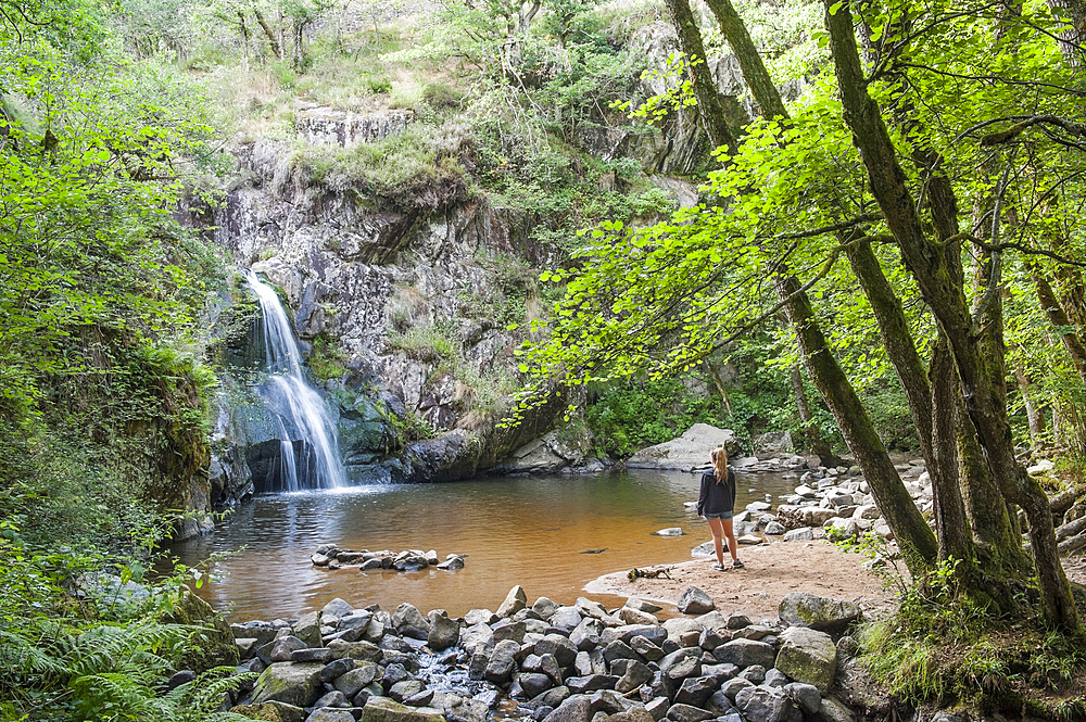 Young girl admiring the Waterfall of Gour Saillant fed by the Auzelle, a sub-tributary of the Sioule River, Saint-Priest-des-Champs, Puy-de-Dome department, Auvergne-Rhone-Alpes region, France, Europe