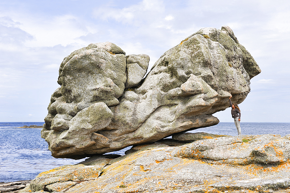 Young girl simulating holding one of the remarkable rocks on Ile de Sein,off the coast of Pointe du Raz,Finistere department,Brittany region,west of France,western Europe