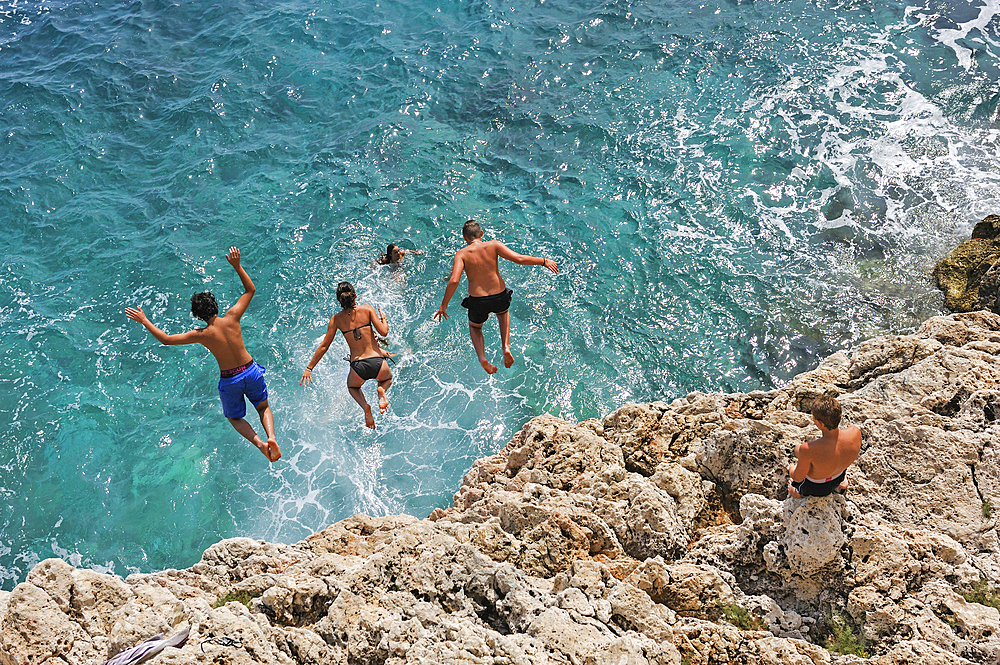 Teenagers diving into the mediterranean sea from the rocky coast near Roquebrune-Cap-Martin, Alpes-Maritimes department,Provence-Alpes-Cote d'Azur region,southeast of France,Europe.